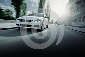 White BMW 3 Series F30 car is driving on asphalt road at summer daytime