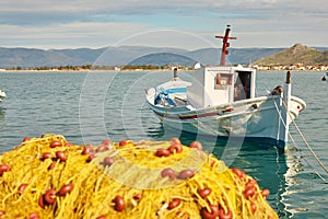 White boat and pile of yellow fishing nets in port