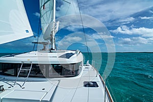 White boat sailing along a calm greenish-blue sea under a bright cloudy sky on a sunny summer day