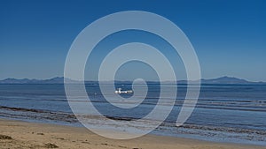 A white boat is visible in the blue ocean.