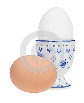 white boiled egg in ceramic egg cup and brown egg