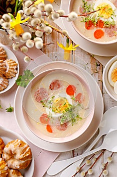 White borscht, polish Easter soup with the addition of white sausage and a hard boiled egg in a ceramic bowl, top view.