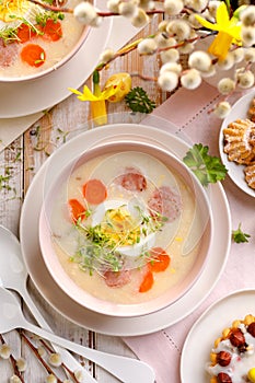 White borscht, polish Easter soup with the addition of white sausage and a hard boiled egg in a ceramic bowl, top view.