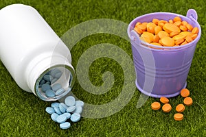 White bottle of blue pills and buckets filled with orange tablets
