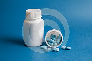White bottle, blue pills, contrasting against blue background   medication and container