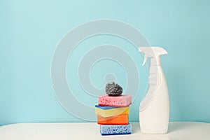 White bottle with cleaning procuct and sponges on blue background with empty space for text photo