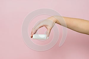 White bottle, drops for eye, nose or ear in hand on pink background. Pharmaceutical product