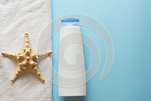 White bottle for shampoo, sea star and towel for bath and spa on blue background. body skin care concept . copy space