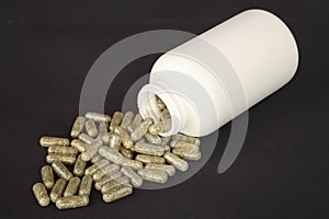 White bottle spilling herb capsules