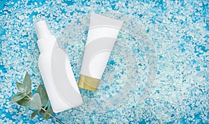White bottles for cosmetics with eucalyptus on the background of sea bath salt