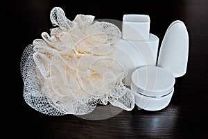 White bottles with creams and washcloths for spa treatments on a dark background. Close-up