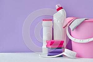 White bottles of household chemicals on a purple background with a copy of space