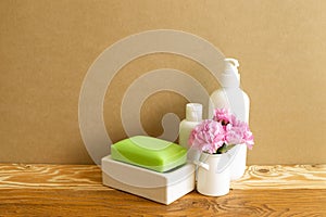 White bottles and soap with flowers on wooden shelf