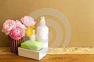 White bottles and soap with flowers on wooden shelf