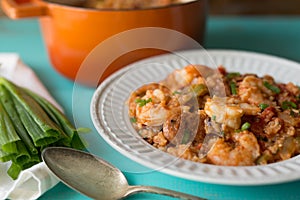 White bowl on a blue table filled with homemade etouffee with shrimp and Andouille sausage.