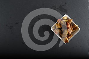 White bowl of candied rheum isolated on black background flat lay