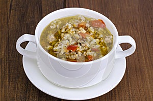 White bowl of chicken and wild rice soup with vegetables