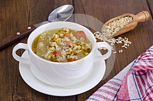 White bowl of chicken and wild rice soup with vegetables