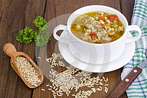 White bowl of chicken and wild rice soup with vegetables