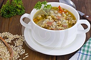 White bowl of chicken and wild rice soup with vegetables