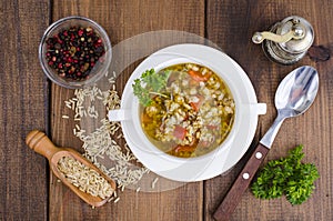 White bowl of chicken and wild rice soup with vegetables