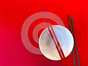 White bowl with chopsticks on red