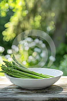 white bowl with fresh asparagus on a wooden background