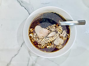 White bowl of instant noodles with minced pork, pork liver, and dried seaweed