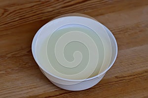 White bowl with milk mousse on a wooden background