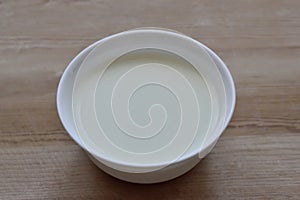 White bowl with milk mousse on a wooden background