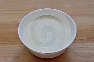 White bowl with milk mousse on a wooden background