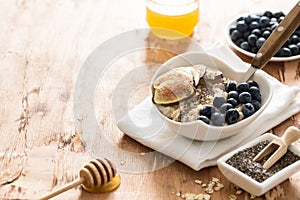 White Bowl of oats porridge with figs, blueberries and chia seeds. Healthy oatmeal breakfast