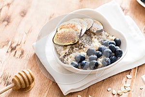 White Bowl of oats porridge with figs, blueberries and chia seeds. Healthy oatmeal breakfast