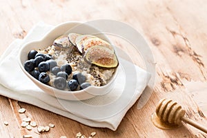 White Bowl of oats porridge with figs, blueberries and chia seeds. Healthy oatmeal breakfast