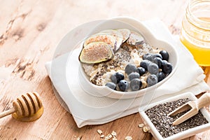 White Bowl of oats porridge with figs, blueberries and chia seeds. Healthy oatmeal breakfast