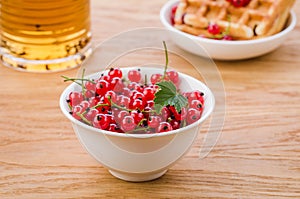 White bowl from red currant with pastries and tea/white bowl from red currant with pastries and tea. Selective focus