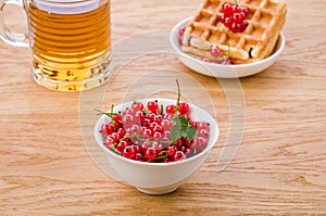 White bowl from red currant, a wafer and a glass of tea/white bowl from red currant, a wafer and a glass of tea. Selective focus