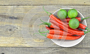 White bowl with red hot chili peppers and lemon on wooden background