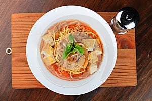 White bowl of soup with some spaghetti and bread pieces decorated with greens