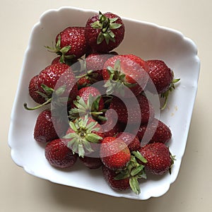 A white bowl of strawberries resting on a table - FRUIT - VEGAN