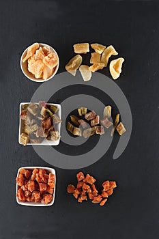 White bowls of candied rheum, pumpkins and cantaloup rock melon isolated on black background flat lay