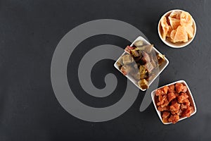 White bowls of candied rheum, pumpkins and cantaloup rock melon isolated on black background flat lay. Image contains copy space