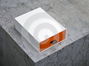 White box with hang tab and orange interior part on concrete table