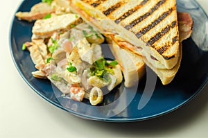 White bread with beechwood smoked bacon, egg, mayonnaise, and tomato served with Caesar pasta with parmesan cheese on the blue photo