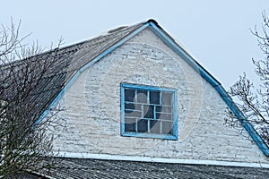 White brick attic of an old rural house with one blue window