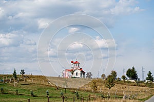 White brick church with red roof in the field