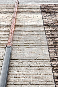 White brick wall and brown brick wall with gray wooden frontal board and copper pipe in temporary protective casing