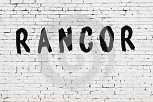 Word rancor painted on white brick wall