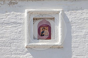 White brick wall of an Orthodox church with a ceramic icon of the Virgin