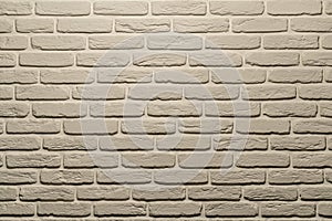 White brick wall of a warm shade lit from above by a lamp. White brick wall, perfect as a background, square photograph